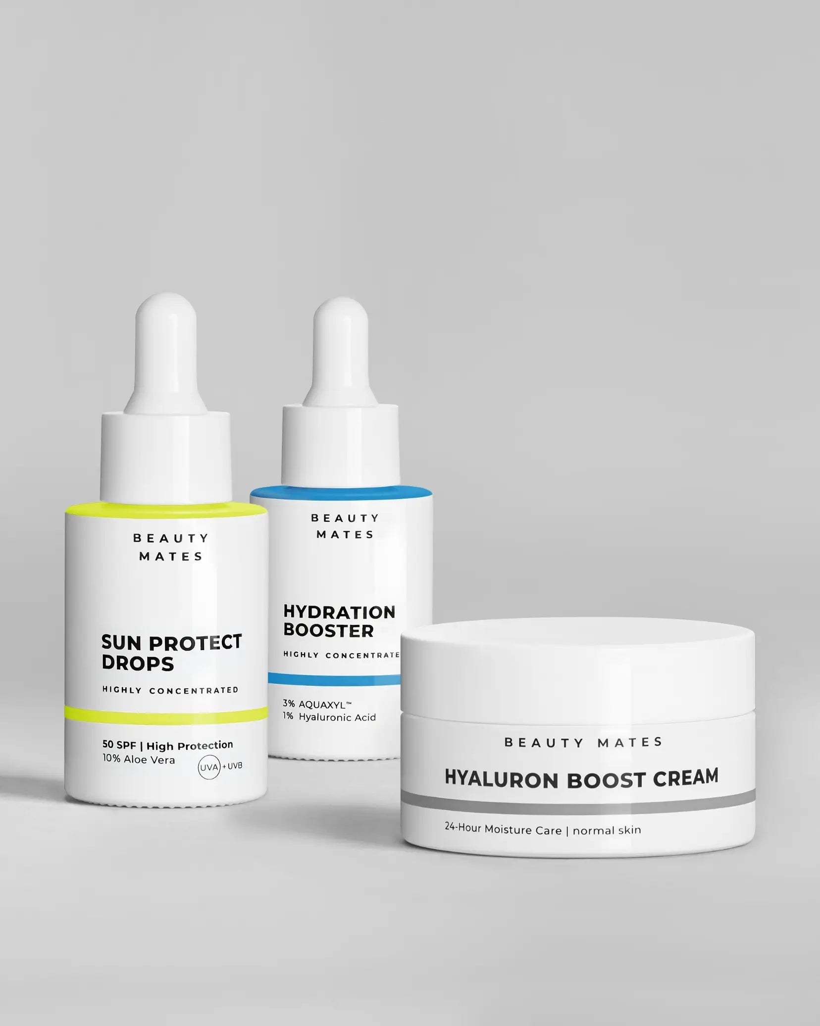 Beauty Mates Sun Protect Drops, Hydration Booster und Hyaluron Boost Cream nebeneinander auf grauem Hintergrund.