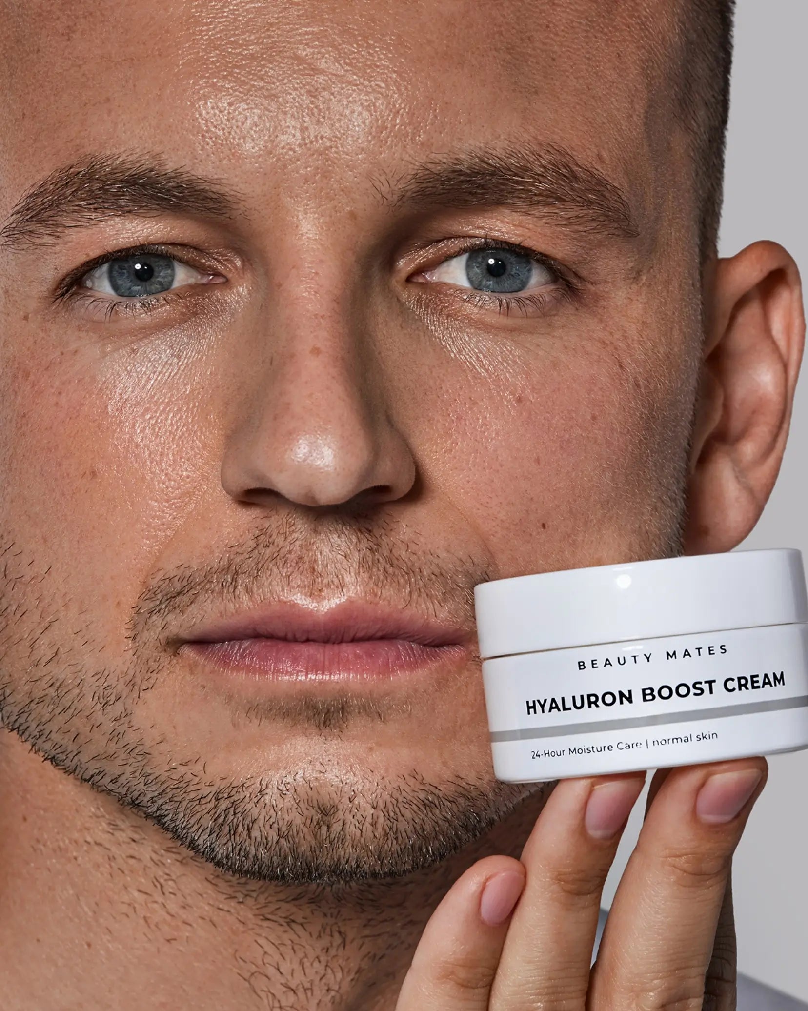 Nahaufnahme eines Mannes, der ein Tiegel Beauty Mates Hyaluron Boost Cream in der Hand hält.